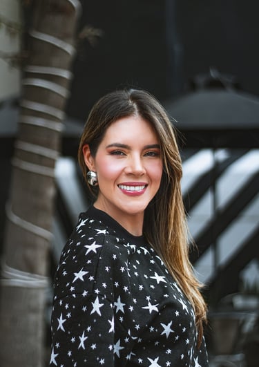 Natalia Devia sonriendo junto a una palmera, suéter negro con estrellas