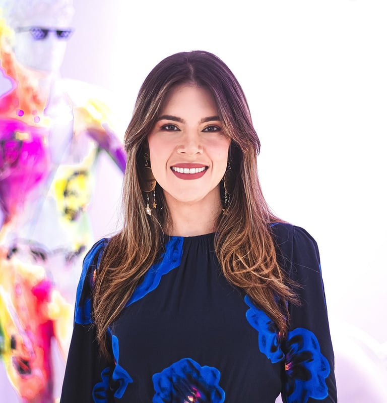 Natalia Devia sonriendo, con vestido azul de flores, frente a arte colorido